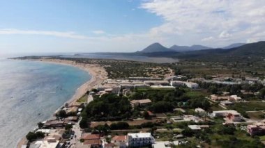 Aerial footage of the beautiful small town known as St George South in the city of Corfu Greece, showing scenic view with mountains and Issos Beach in the background