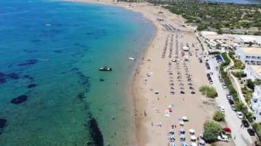 Aerial footage of the beautiful small town known as St George South, Greek city of Corfu Greece, showing people relaxing on the beach with hotels in the background on the Issos Beach