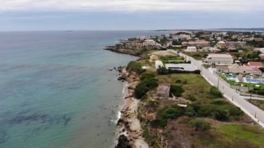 Aerial footage of the beautiful small town known as St George South in the city of Corfu Greece, showing the beautiful beach and coast on a bring sunny summers day in the village.