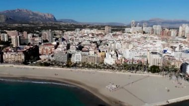 Aerial footage of the Spanish town of Benidorm in Alicante, showing the high-rise hotels and apartments and the beautiful sandy north side beach taken on a sunny day at the old town area of Benidorm