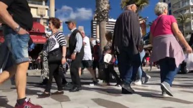 Footage taken on Benidorm's main strip showing people walking along the beach front on a bright sunny day.