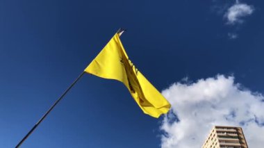 Yellow Benidorm beach SOS flag slow motion footage blowing in the wind on a clear blue sky day with a couple of clouds in the Sky.