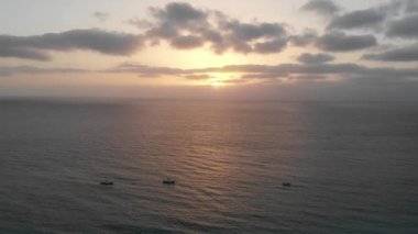 Beautiful sunset over the beautiful beach of Cape Verde on a part cloudy night showing fishing boats in the ocean and the waves of the ocean.