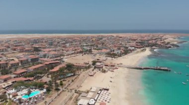 Aerial footage of the famous pier at Cape Verde, fishermen with fishermen's wives selling the fish on the pier, taken in Cape Verde (Capo Verde) on a beautiful sunny say showing the clear. blue ocean.