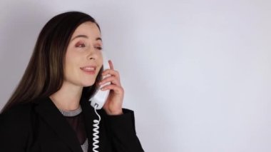 İş elbisesi giymiş genç bir kadın telefona cevap veriyor ve eski 90 'ların telefon ahizesinde romantik bir şekilde flört ediyor.