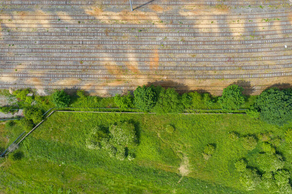 Top down aerial photo of old abandoned railway train tracks in the summer time along side a bunch of green trees.