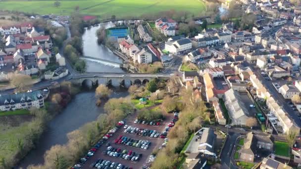 英国西ヨークシャーのウェザビーの町の中心部の空中映像 冬に撮影された町の中心部につながる小さな橋を渡ってトラフィック駆動と川の波止場を示しています — ストック動画