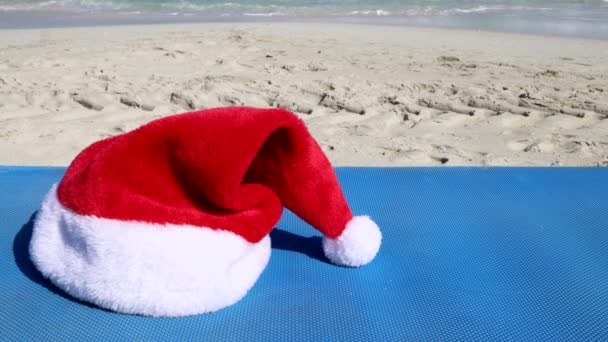 キューバの美しいビーチの映像バラデロ 青いサンラウンジャーの側に配置されている赤いクリスマスのサンタの帽子を示す 太陽とビーチのコンセプトでクリスマス 8K品質で撮影 — ストック動画