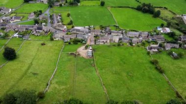 Aerial footage of the beautiful village of Thoralby in the Richmondshire district of North Yorkshire in the UK, showing the small British village and surrounding green fields in the summer time
