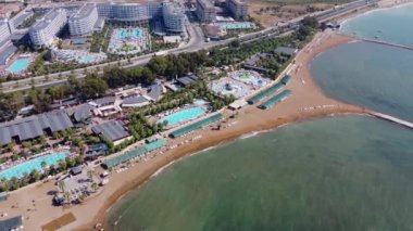 Türkiye 'nin güzel sahil beldesi Alanya, Antalya' nın insansız hava aracı görüntüleri, yaz mevsiminde sıcak bir günde Türk sahil plajı önü ve su parkını gösteriyor.