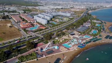 Türkiye 'nin güzel sahil beldesi Alanya, Antalya' nın insansız hava aracı görüntüleri, yaz mevsiminde sıcak bir günde Türk sahil plajı önü ve su parkını gösteriyor.
