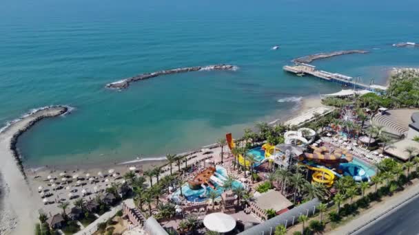 トルコのアンタルヤの美しいビーチリゾートの空中ドローン映像暑い晴れた日に夏の時間にトルコの海岸沿いのビーチフロントとウォーターパークを示す — ストック動画