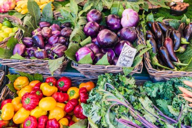 Sebze pazarında patlıcan. Hasır sepetlere doldurulmuş çeşitli renkli sebzeler ve 4 avroluk fiyat etiketi.