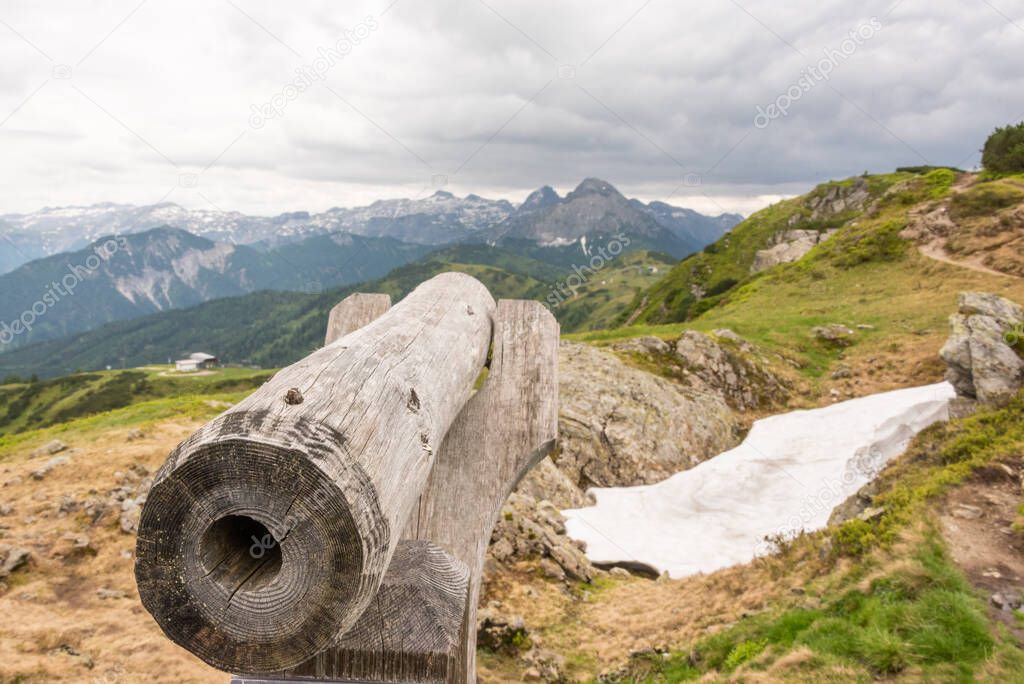 A wooden telescope for observing the top of the mountain. Hiking trail in Austria. In the background, snowy mountains. Flachau