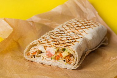 Shawarma 'yı sarı arka planda ambalaj kağıdında hazırlayın. Fast food.