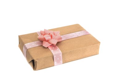 Kahverengi kağıda sarılmış ve beyaz arka planda pembe kurdeleyle bağlanmış bir hediye. İzole edilmiş.