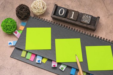 Kitap ayracı ve kahverengi arka planda sarı çıkartmalar olan gri haftalık planlamacı. İş planlaması ve kişisel büyüme kavramı