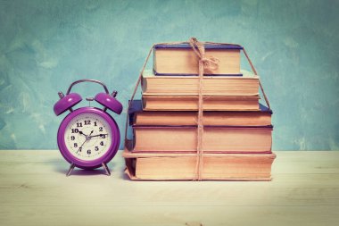 Çalar saat ve sicimle bağlanmış harap olmuş kitaplar. Eğitim ve bilgelik kavramı