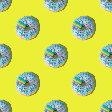 Sarı arka planda gökkuşağı olan tekrarlayan mavi donut deseni. Düz yatıyordu.