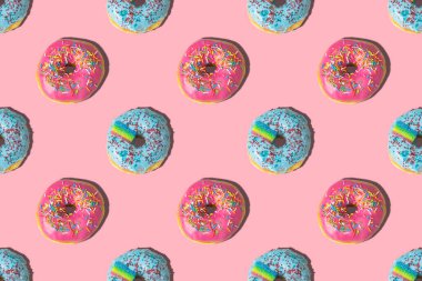 Pembe arka planda tekrarlanan pembe ve mavi donut deseni. Düz yatıyordu.