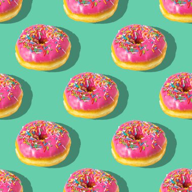 Yeşil arka planda tekrarlanan pembe donut deseni. Düz yatıyordu.