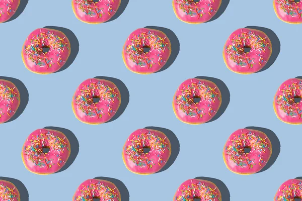 蓝色背景上粉色甜甜圈的重复图案 平躺在床上 — 图库照片