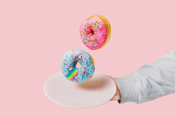 Dois Donuts Multicoloridos Pairam Sobre Uma Placa Segurada Por Uma Imagem De Stock