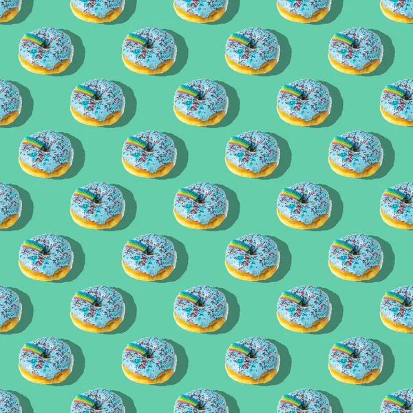 Ένα Επαναλαμβανόμενο Μοτίβο Από Μπλε Ντόνατς Ουράνιο Τόξο Πράσινο Φόντο — Φωτογραφία Αρχείου