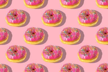 Pembe arka planda tekrarlanan pembe donut deseni. Düz yatıyordu.