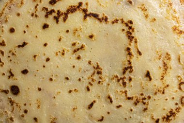 Pancake surface texture and pattern. Close-up of thin hot pancakes in a plate. Traditional rustic food. Graphic resource. Table top view.