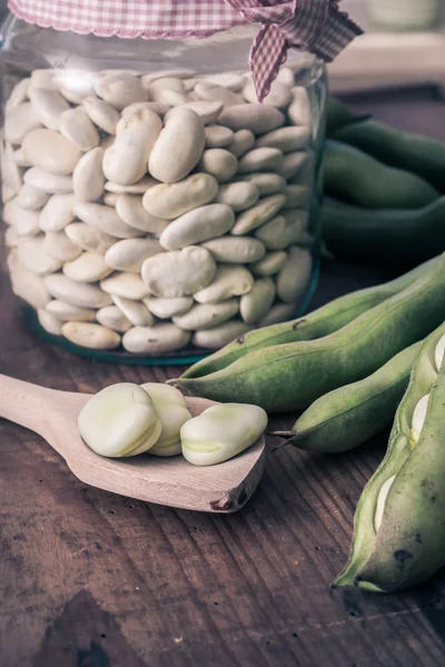 Tuinbonen op een houten tafel met jar, vol met droge bonen — Stockfoto