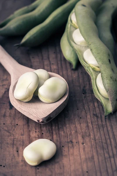 Frijoles anchos sobre una mesa de madera con cuchara —  Fotos de Stock