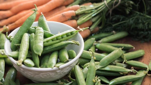 Vainas de guisante en un tazón con zanahorias —  Fotos de Stock