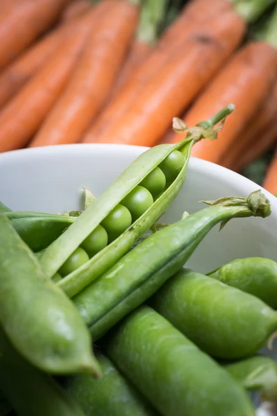 Ärt pods i en skål med morötter — Stockfoto