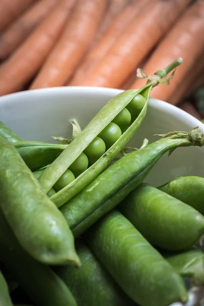Pea pods in a bowl with carrots — Stock Photo, Image