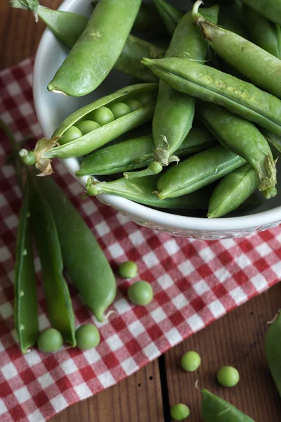 Pea pods in a bowl on wooden Table — Stock Photo, Image