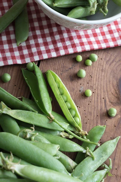 Ärt pods i en skål på träbord — Stockfoto