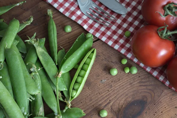 Erwt peulen in een kom op houten tafel — Stockfoto