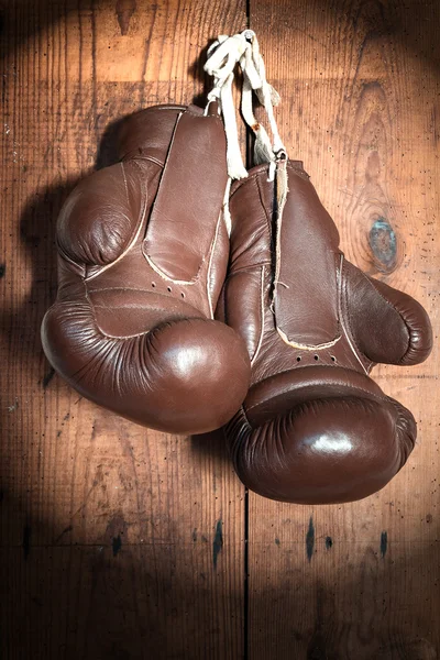 Vecchi guanti da boxe, su parete in legno sotto i riflettori — Foto Stock