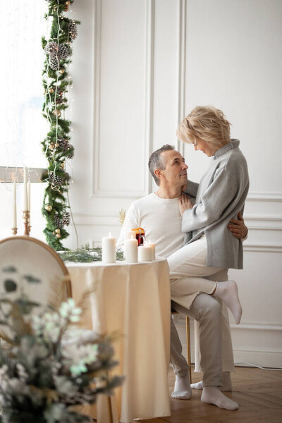 adult man and woman hugging sitting near a round festive table