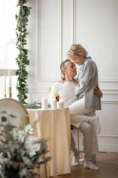adult man and woman hugging sitting near a round festive table
