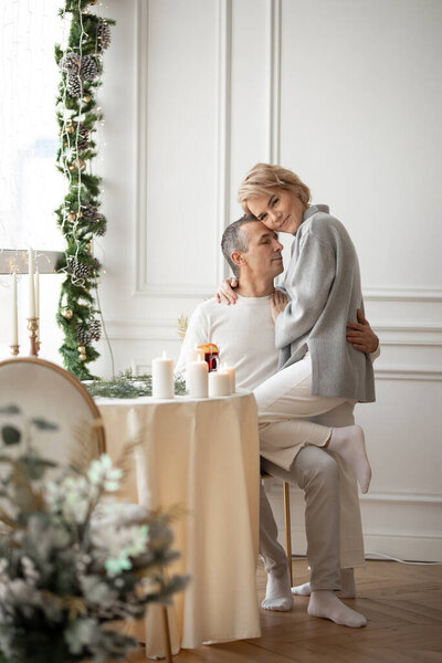 adult man and woman hugging sitting near a round festive table