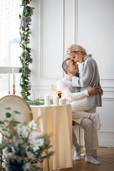 adult man and woman hugging sitting near a round festive table