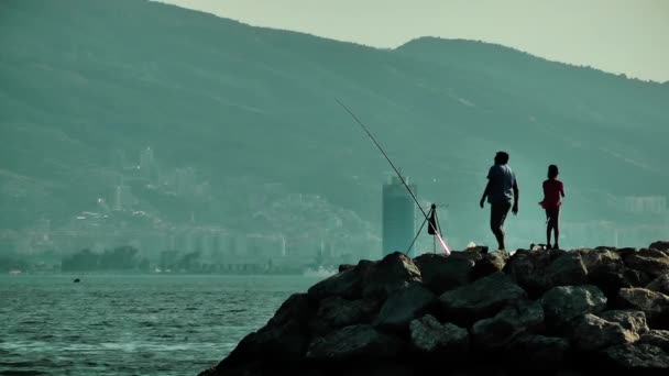 Pêcheur et un enfant sur les rochers — Video