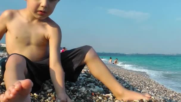 Ребенок играет с камнями возле пляжа — стоковое видео