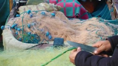 balıkçı file çorap onarır.