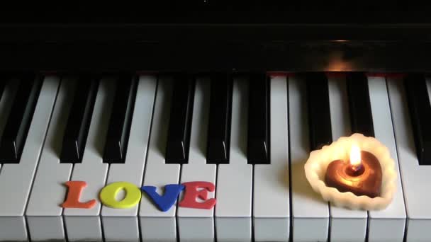 Amor en las teclas de piano y luz de la vela — Vídeos de Stock
