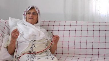 yaşlı kadın ile tesbih dua ediyor.