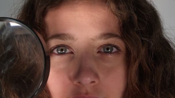 虫眼鏡を通して見ている若い女の子は — ストック動画