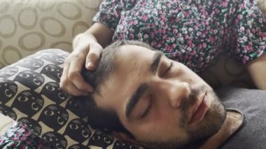 Bir kadın eli genç bir adamın saçına masaj yapar.